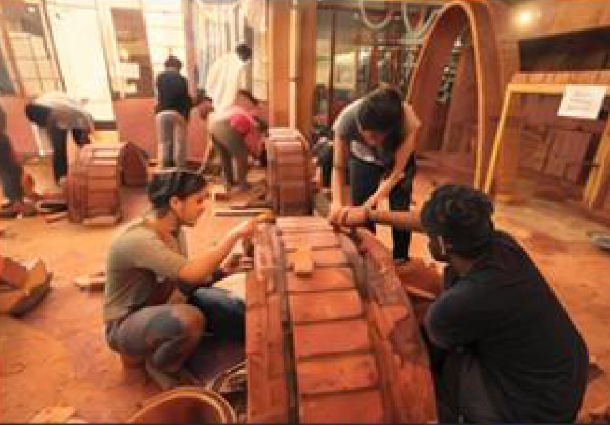 Participants shaping compressed earth blocks together at an earth building workshop.