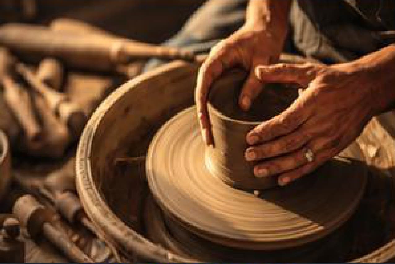 A potter shaping clay on a wheel during a pottery workshop.