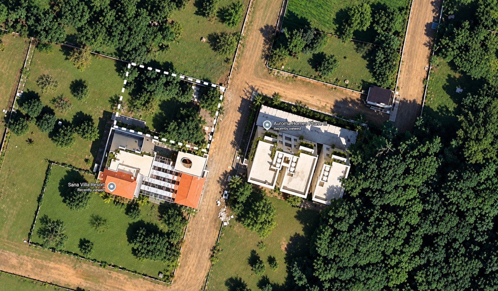 Top-down aerial view of the villa plot, outlined with a dotted line, among tree-lined plots beside Auroma Homes Phase III.