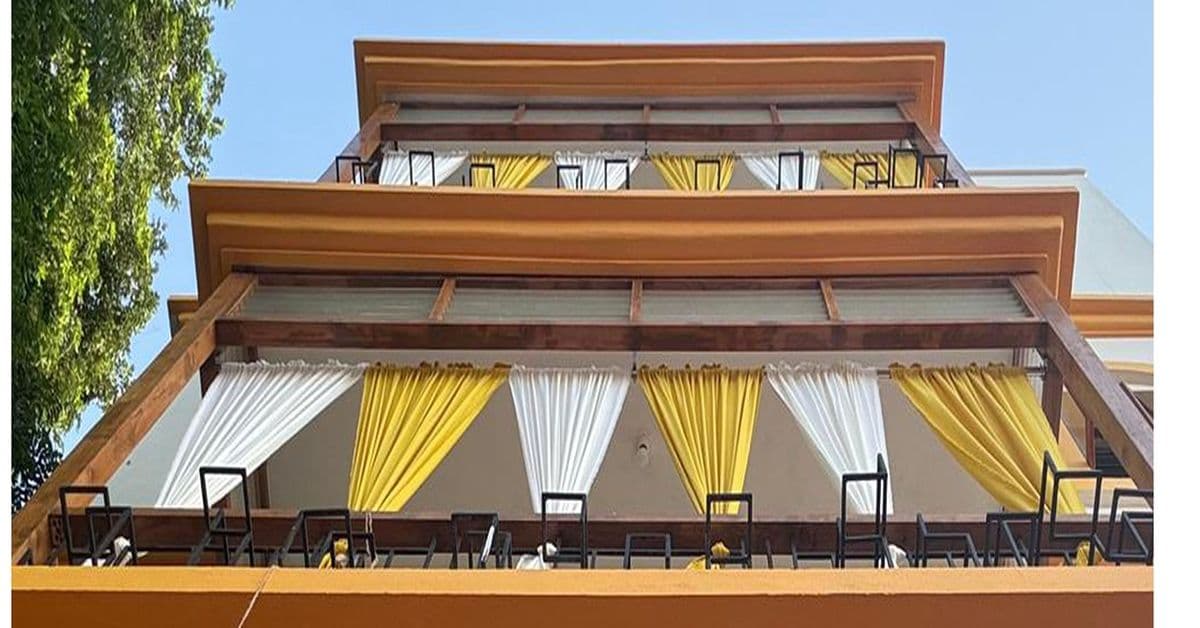Auroma Phase IV — a terrace with a wooden pergola and yellow-and-white drapes.